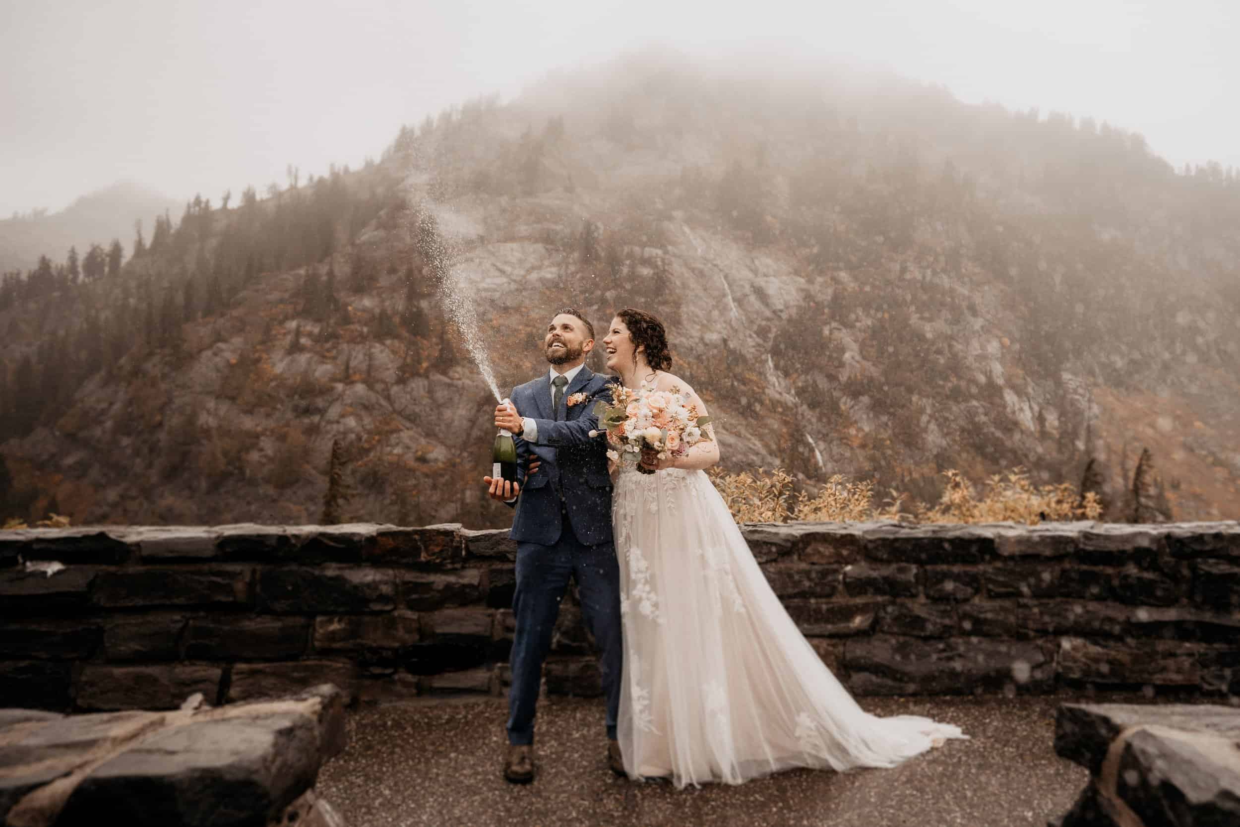 couple popping champagne in their mountain elopement location