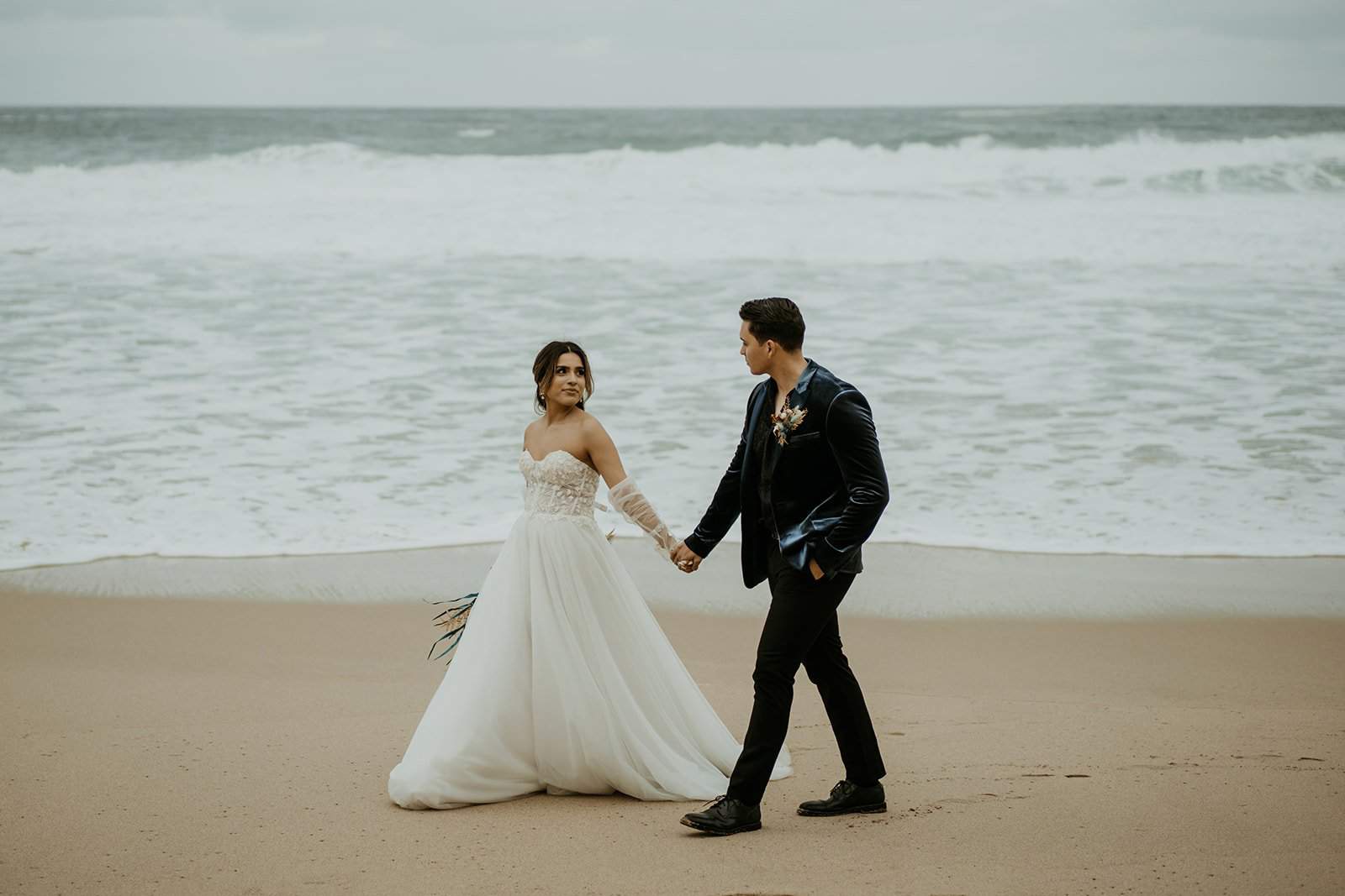 Bride and groom holding hands, walking along the beach during their elopement in Hawaii